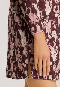 Krátké šaty z burgundské tkaniny s paisley vzory v růžové a bílé barvě. Mají dlouhé rukávy a postranní rozparek.