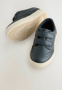 Ciemnoniebieskie skórzane buty z dwoma rzepami, perforowanym wzorem na palcach oraz kremową gumową podeszwą z teksturowanym wzorem antypoślizgowym.