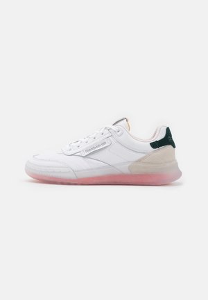 Baskets Reebok basses blanches avec semelle translucide rose, lacets blancs, détail beige au talon et languette de talon vert foncé sur fond blanc.