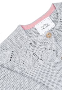 Maglione lavorato a maglia grigio chiaro con rifinitura del colletto rosa, bottone in legno e dettagli a motivo foglia. Etichetta con la scritta "Stellen & Friends."
