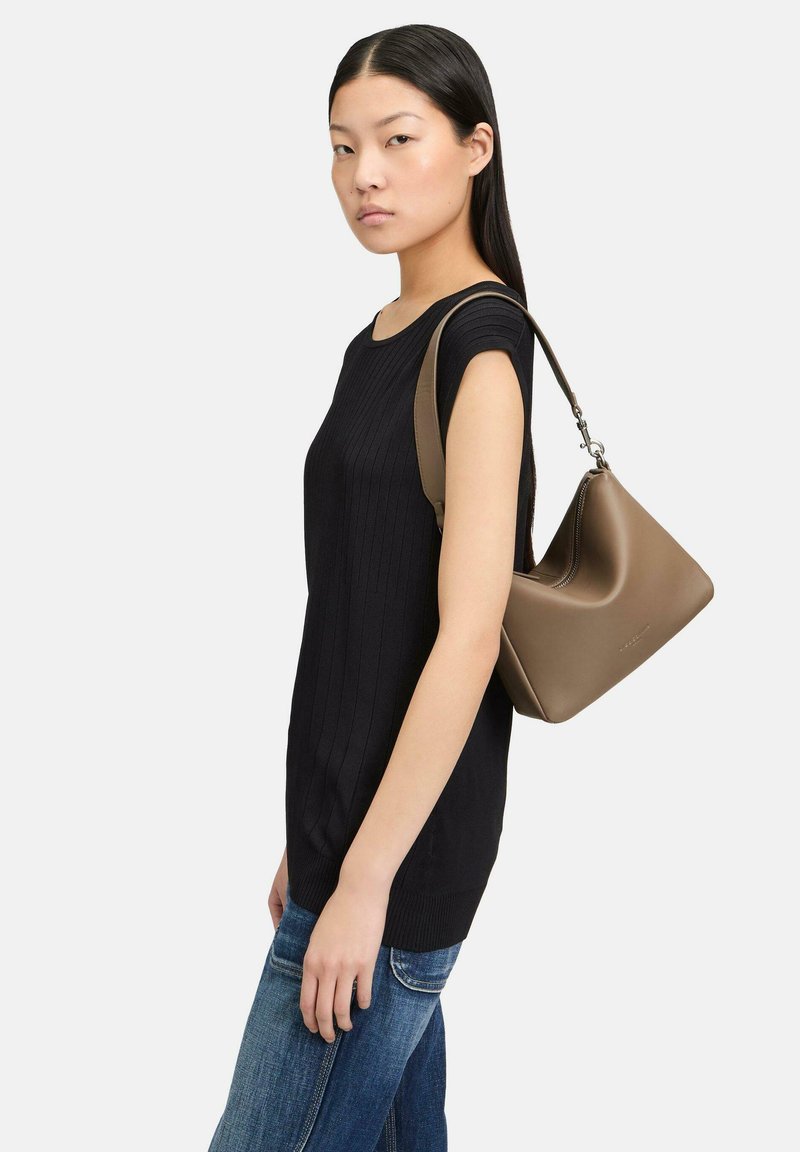 Czarny, prążkowany top z krótkimi rękawami, zestawiony z niebieskimi dżinsami. Brązowa skórzana torba na ramię zwisa z jednego ramienia.