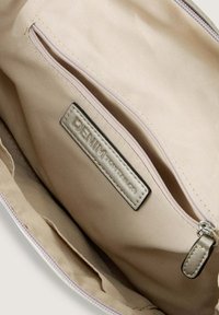Interno di una borsa in tessuto beige, con una tasca con cerniera e un'etichetta metallica che riporta la scritta "DENIM TOM TAILOR". Texture liscia, design minimale.