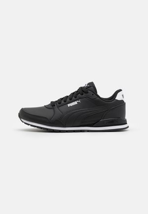 Baskets noires Puma avec semelle blanche et logo Puma, vue de côté sur un fond clair uni.