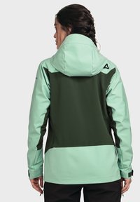 Water-resistant jacket in mint green and dark green. Features a hood, smooth texture, zippered pockets, and a contrasting design on the back.