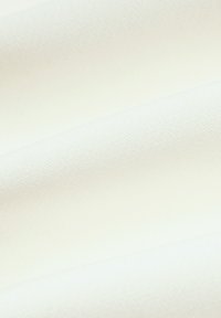 Biała tkanina o teksturowanej powierzchni, złożona w sposób ukazujący gładkie krzywe i miękkie fałdy. Materiał wydaje się lekki i elastyczny.