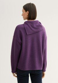 Lila gestrickter Pullover mit großem, umgeschlagenem Kragen und langen Ärmeln. Strukturiertes Material mit lässiger Passform und geradem Saum.
