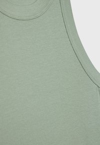 Vihreä ribattu hihaton paita, jossa on pyöreä pääntie ja sileä pinta. Kankaassa on hienovarainen kiilto ja joustava venyvyys mukavuutta varten.