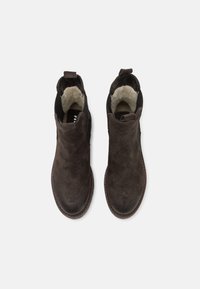 Paire de bottines en daim marron foncé avec bouts ronds et doublure en fourrure claire visible à l'intérieur, vues de dessus sur fond blanc.