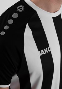Maillot de sport rayé noir et blanc avec un col rond, présentant un logo sur l'épaule et des accents circulaires le long de la manche.