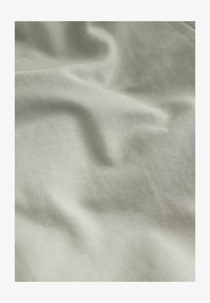 Světle zelená látka s hladkým, mírně texturovaným povrchem, který má jemné záhyby a měkký matný vzhled.
