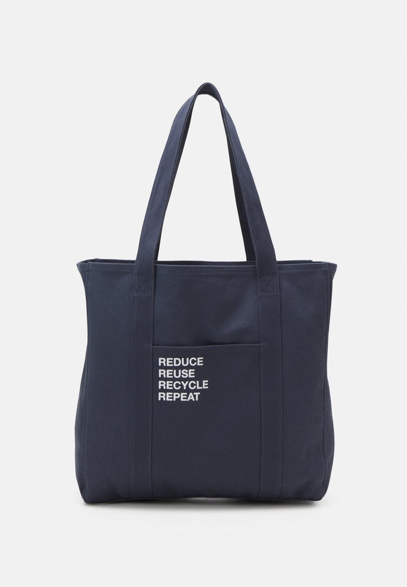 Sac cabas en toile marine avec deux poignées et une poche frontale, arborant un texte blanc indiquant "RÉDUIRE RÉUTILISER RECYCLER RÉPÉTER." Design simple.