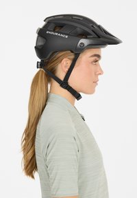 Schwarzer Mountainbike-Helm mit Belüftungslöchern und verstellbaren Riemen, auf dessen Seite der Text "ENDURANCE" aufgedruckt ist.