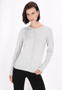 Cardigan grigio chiaro con scollo arrotondato, maniche lunghe e chiusura a cinque bottoni. Presenta dettagli a coste sull'orlo e sui polsini. Texture liscia.