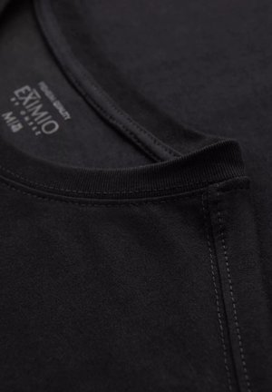 Černé bavlněné tričko s límcem, které má hladkou texturu, kulatý výstřih a zesílené švy. Na štítku jsou uvedeny informace o značce.