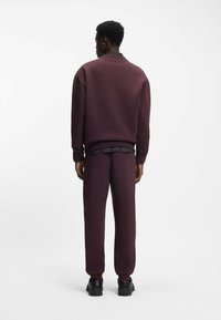 Burgundy sweatshirt and pants set made from soft fabric, featuring relaxed fit, ribbed cuffs, and a textured inner lining.