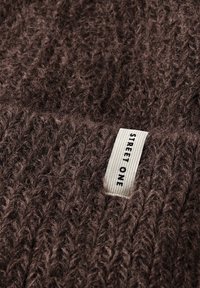 Tessuto di maglione lavorato a maglia marrone con un aspetto morbido e texturizzato. Presenta un'etichetta bianca visibile con il testo "STREET ONE."
