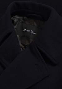 Jūras spēku vilnas mētelis ar platu apkakli, ar gludu satīna oderi. Metāla birka ar "Matinique" marķējumu redzama apkakles iekšpusē.