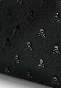 Bolso de cuero negro texturizado con adornos metálicos de calavera y huesos cruzados. El patrón está uniformemente distribuido por toda la superficie.