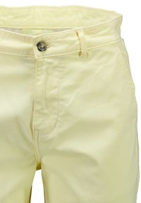 Pantalon jaune clair avec fermeture à boutons, passants de ceinture et poche latérale visible sur le côté droit, vue de face.