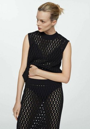Top negru tricotat fără mâneci, cu un model texturat și cu găuri deschise; asortat cu o fustă care prezintă același design și material.