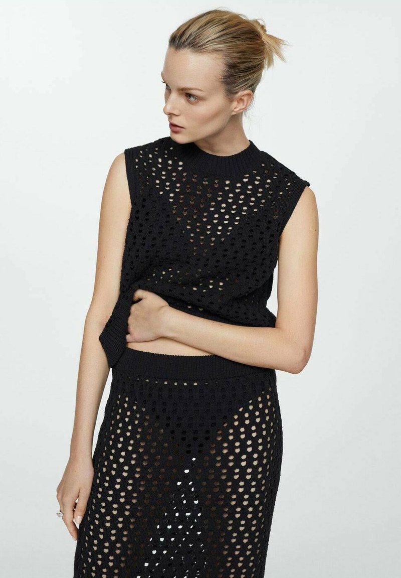 Top negru tricotat fără mâneci, cu un model texturat și cu găuri deschise; asortat cu o fustă care prezintă același design și material.