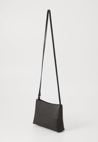 Čierna crossbody taška so hladkou kožou navrchu a textúrovanou vzorovanou tkaninou na dne. Nastaviteľný popruh a obdĺžnikový tvar.