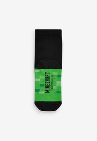 Sort crew-sok med grønt Minecraft-tema mønster, der indeholder pixelgrafik og tekst. Lavet af et blødt, strækbart stof for komfort.