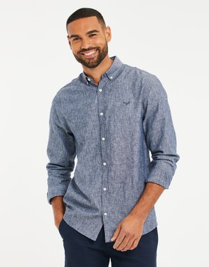 Camisa de manga larga para hombre en tejido azul texturizado, con cuello abotonado, botones frontales y pequeño logo en el pecho. Corte entallado, mangas enrolladas.