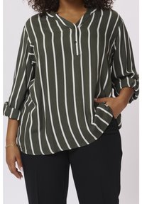 Blouse à rayures vertes et blanches avec col et détail de boutons, manches retroussées et ourlet arrondi, conçue en tissu léger.