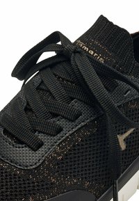 Schwarzer Sportschuh mit strukturiertem Obermaterial, weiterem Mesh-Gewebe und kontrastierenden bronzefarbenen Akzenten. Enthält runde Schnürsenkel und eine Gummisohle.