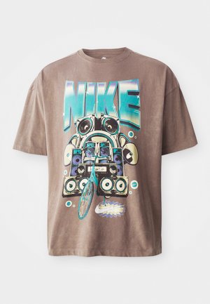 Brun bomulds t-shirt med et iøjnefaldende, farverigt grafik af en boombox og en cykel. Designet inkluderer ordet "NIKE" i store blå bogstaver.