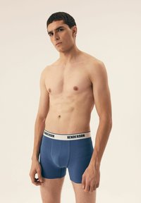 Męskie niebieskie bokserki wykonane z miękkiego materiału z białą gumką z czarnym napisem "HENDERSON", zapewniające dopasowane fason.