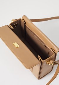Tan leren handtas met een gestructureerd ontwerp, gouden hardware, een bovenklep-sluiting en een binnens compartiment voor organisatie.