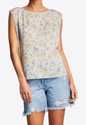 Bezrękawnik w kwiaty z teksturowanym, żeberkowanym wzorem w pastelowych kolorach. W połączeniu z jasnoniebieskimi szortami jeansowymi z postrzępionym wykończeniem i przetarciami.