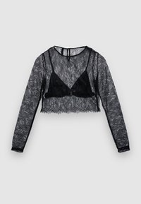 Schwarzes Spitzen-Crop-Top mit langen Ärmeln und einem dreieckigen Bralette-Design darunter. Es zeichnet sich durch transparente Textur, ein kompliziertes Spitzenmuster und gezackte Kanten aus.