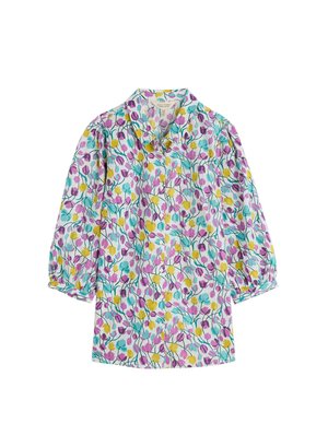 Bloem blouse van lichtblauwe stof met paarse, gele en groene bloempatronen. Beschikt over een kraag en pofmouwen.