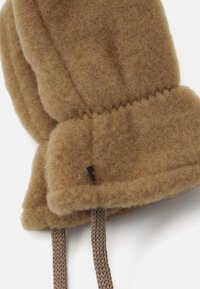 Brauner Filzhut mit abgerundeten Kanten, einer strukturierten Oberfläche und dekorativen geflochtenen Bändern. Enthält ein kleines schwarzes Markenetikett.