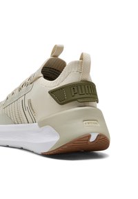 Beige Schuh mit strukturiertem Strickobermaterial, einer dicken weißen und braunen Sohle und einem grünen Akzent an der Ferse, der das Markenlogo zeigt.
