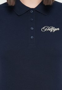 Polo navy de tejido texturizado, con una tapeta de botones y el logo "Hilfiger" bordado en hilo claro.
