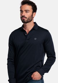 Marineblaue Langarm-Polo mit weichem Material, klassischem Kragen, drei Knöpfen und einem dezenten Logo auf der Brust.