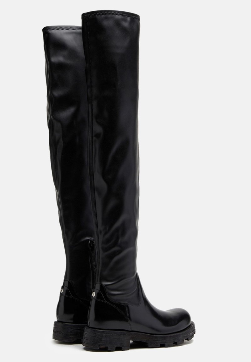 Botas negras hasta la rodilla con un acabado brillante, cremallera lateral, suela de goma gruesa y una textura suave. El diseño se centra en la funcionalidad.