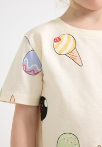 Crème-kleurig katoenen t-shirt met kleurrijke ijscocone graphics in verschillende patronen. Korte mouwen en een ronde halslijn.