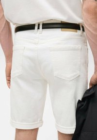 Weiße Denimshorts mit umgeschlagenen Säumen, zwei Gesäßtaschen und einem schwarzen Bund. Der Stoff hat eine strukturierte Oberfläche.