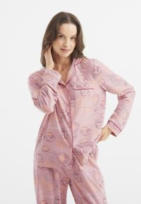 Hellrosa Schlafanzug-Set mit verschiedenen Frühstücksillustrationen, darunter Tassen und Croissants, im Button-Up-Design mit Tasche.