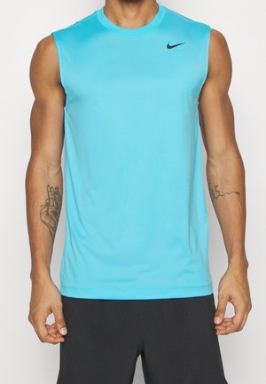 Mand iført en knaldblå ærmeløs sportstrøje med sort Nike-logo og sorte shorts, som viser tatoveringer på begge underarme.