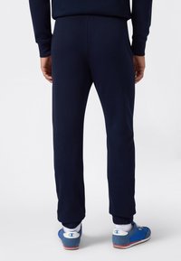 Marine sweatpants met elastische boorden, gemaakt van zachte stof. Zichtbaar logo op blauwe sneakers met witte accenten en een laag profiel.
