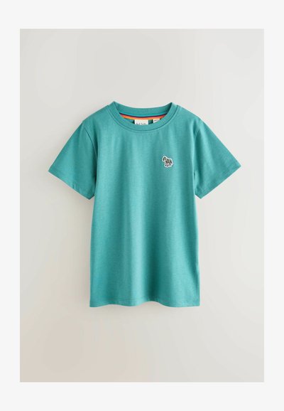 Teal puuvillane t-särk lühikeste varrukatega, ribaga ümmargune kaelus ja väikese tikandiga disain rinnapeal. Sile tekstuur, lõdvestunud stiil.