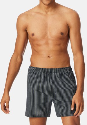 Gestreifte Boxershorts in Dunkelblau mit weißen vertikalen Streifen, elastischem Bund und einem einzelnen Knopfdetail an der Vorderseite. Weicher Baumwollstoff.