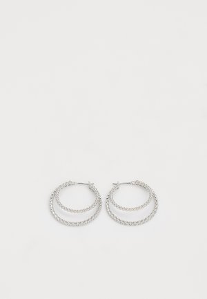 Strieborné kruhové náušnice s dvoma sústrednými prstencami; jeden hladký a druhý s korálikovou textúrou, zabezpečené zatváraním na kolík.