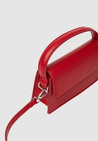 Sac à main en cuir rouge avec un design structuré, une poignée supérieure et une bandoulière amovible. Présente une texture lisse et des accents en métal argenté.